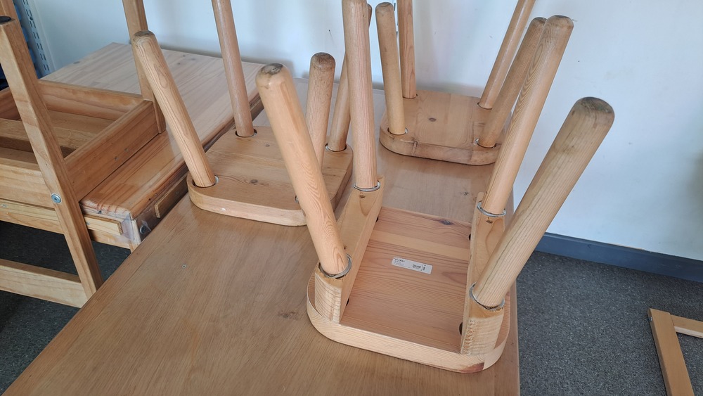 Les petits tabourets en bois de la classe, retournés sur une table en fin de journée